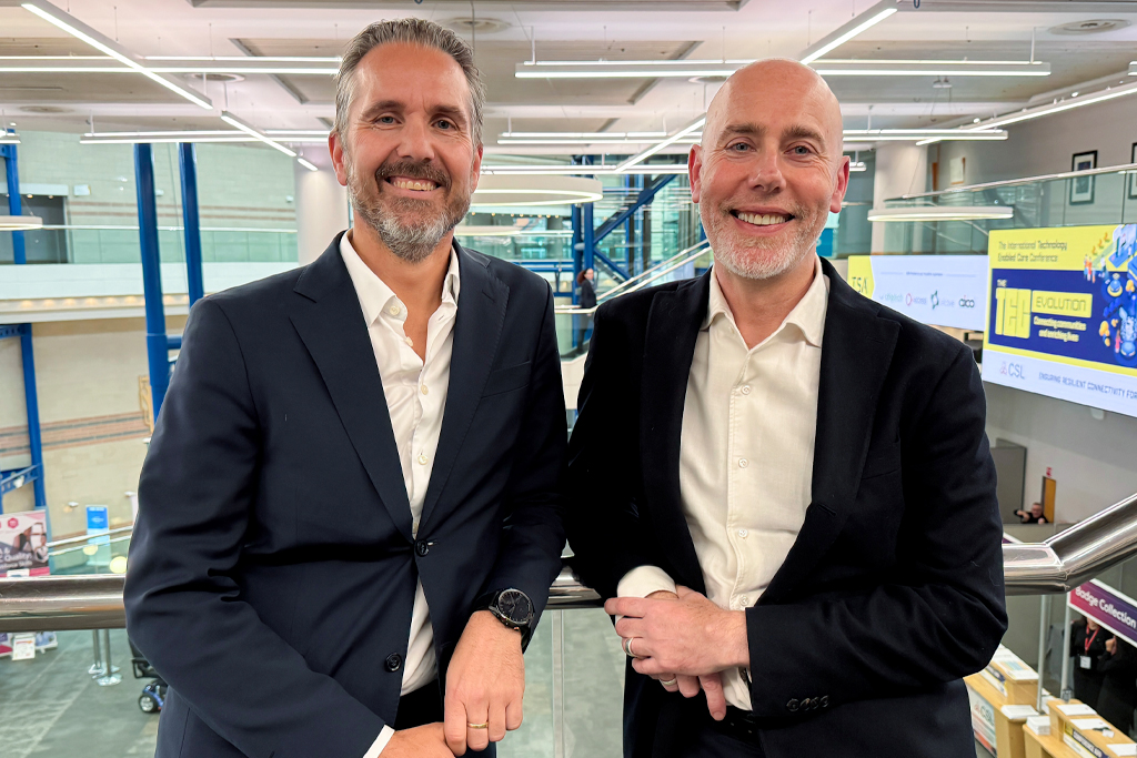 Two men in smart suits stand side by side, leaning on a glass railing and smiling at the camera. On the left is Geir Tore Jakobsen, the CEO for HEPRO. On the right is David Hammond, CEO of Chiptech UK & Europe.
